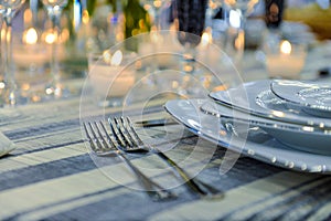 Table setting with blank guest card on empty white plate and cutlery on table,