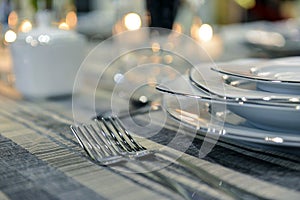 Table setting with blank guest card on empty white plate and cutlery on table