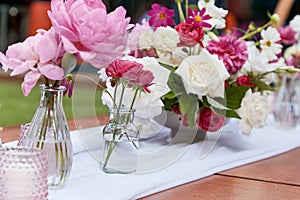 Table setting with candles and textured pink and white flowers. Event decor inspiration, garden party