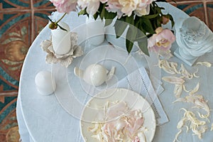 Table setting with a cup of tea and white peonies in a white ceramic jug