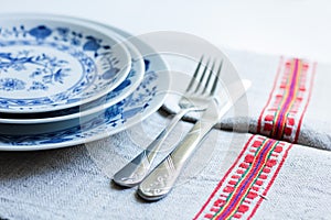 Table setting for dinner: a plate, a fork, a knife on a woven cloth napkin with an embroidered pattern,  traditional handmade in