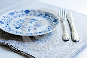Table setting for dinner: a plate, a fork, a knife on a woven cloth napkin with an embroidered pattern,  traditional handmade in