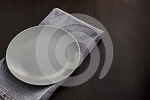 table setting with empty plate and napkin on black background copyspace