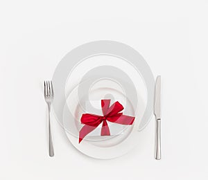 Table setting with a gift box with a red bow in a plate on a white background. Valentines Day, Mothers Day, Birthday or Christmas