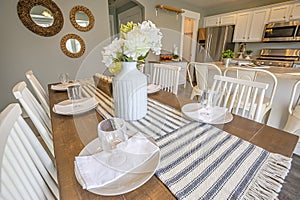 Table setting inside a dining room with brown table and white chairs