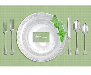 Table setting with plate, spoon, knife and fork on a green fabric background photo