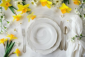 table setting. Plates and cutlery with spring flowers daffodils on a light table.