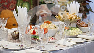 Table setting. Plates with snacks are beautifully placed on the festive home table. Dinner dishes and glasses are placed
