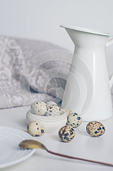 Table setting with quail eggs, jug, spoon and linen napkin