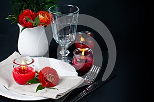 Table setting with red buttercups on a black background