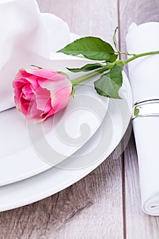 Table setting with a single pink rose