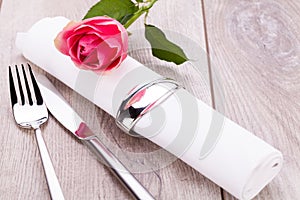 Table setting with a single pink rose