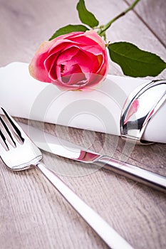 Table setting with a single pink rose