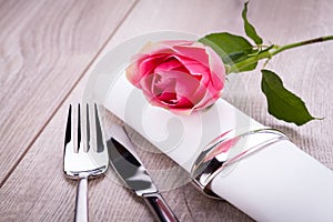 Table setting with a single pink rose