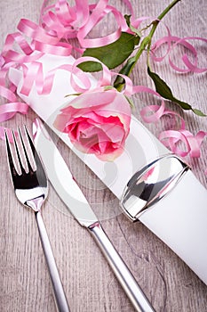 Table setting with a single pink rose