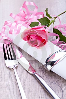 Table setting with a single pink rose