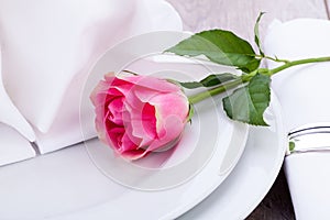 Table setting with a single pink rose