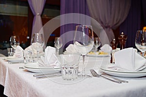 Table setting with sparkling wineglasses, plates with white napkins and cutlery on table, copy space.