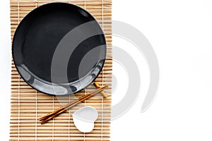 Table setting for sushi roll. Empty plate on mat near chopstick and bowl for sause on white background top view