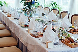 Table setting. Table served for wedding banquet, close up view. White napkin on a white empty plate on dining table