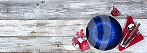 Table setting for Valentines Day celebration in flat lay format with blue plate, red hearts, napkin, silverware and drinking glass