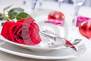 Table setting for valentines or wedding day with red roses. Romantic table setting for two with roses plates cups and cutlery