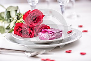 Table setting for valentines or wedding day with red roses. Romantic table setting for two with roses plates cups and cutlery