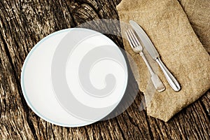 Table setting with vintage silverware or cutlery and empty plate on rustic wood. Top view.