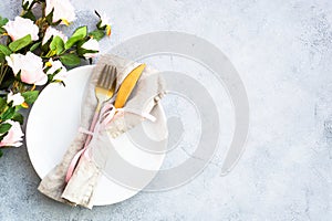 Table setting with white plate, cutlery and flowers.