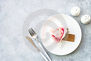 Table setting with white plate, cutlery and flowers.