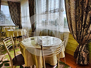 A table in a small cozy cafe or restaurant with a window and curtains. Dimmed lights, beautiful Design of the hall