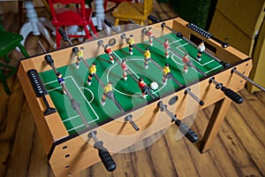Table soccer. Foosball in a children`s playroom. Close-up during the game. Soccer table kid`s home toys, football family game