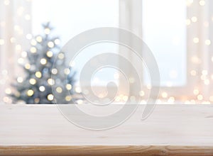 Table with space against blurred Christmas tree and decorated window