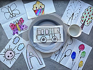 On the table are spread out children`s drawings, depicted on a napkin, for children`s craft
