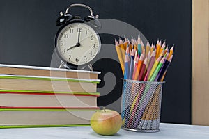 On the table a stack of books with an alarm clock on top, a snack break