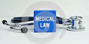 On the table is a stethoscope and a blue cube with the inscription - MEDICAL LAW