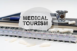 On the table is a stethoscope, a diary and a piece of paper with the inscription - Medical Tourism