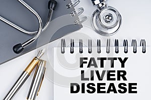 On the table are a stethoscope, a pen and a notebook with the inscription - FATTY LIVER DISEASE