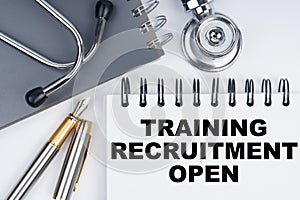 On the table are a stethoscope, a pen and a notebook with the inscription - TRAINING RECRUITMENT OPEN