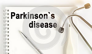 On the table are a stethoscope, a thermometer, a pen and a notebook with the inscription -Parkinsons disease