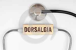 On the table is a stethoscope and a wooden plate with the inscription - DORSALGIA