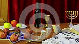 On the table in the synagogue are the symbols of Rosh Hashanah: treats and shofaras next to the Talith and candles.