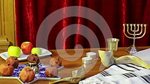 On the table in the synagogue are the symbols of Rosh Hashanah: treats and shofaras next to the Talith and candles.