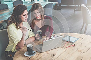 On table is a tablet computer, a smartphone and glasses. Girl is pointing at computer screen. Brainstorming.