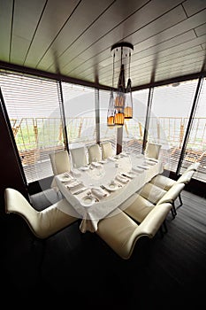 Table and ten white chairs in empty restaurant photo