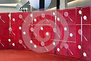 Table tennis and badminton rackets are hung on a red square grill steel grid, used as a backdrop for various events