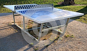 Table tennis blue table blue color net is made of metal around pebbles and sun lawn