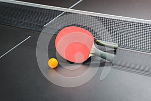 Table tennis racket with ball on black table