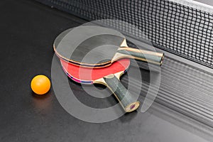 Table tennis racket with ball on black table