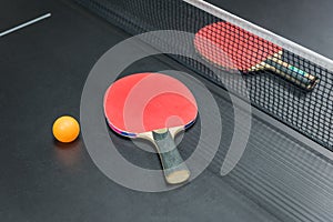Table tennis racket with orange ball on black